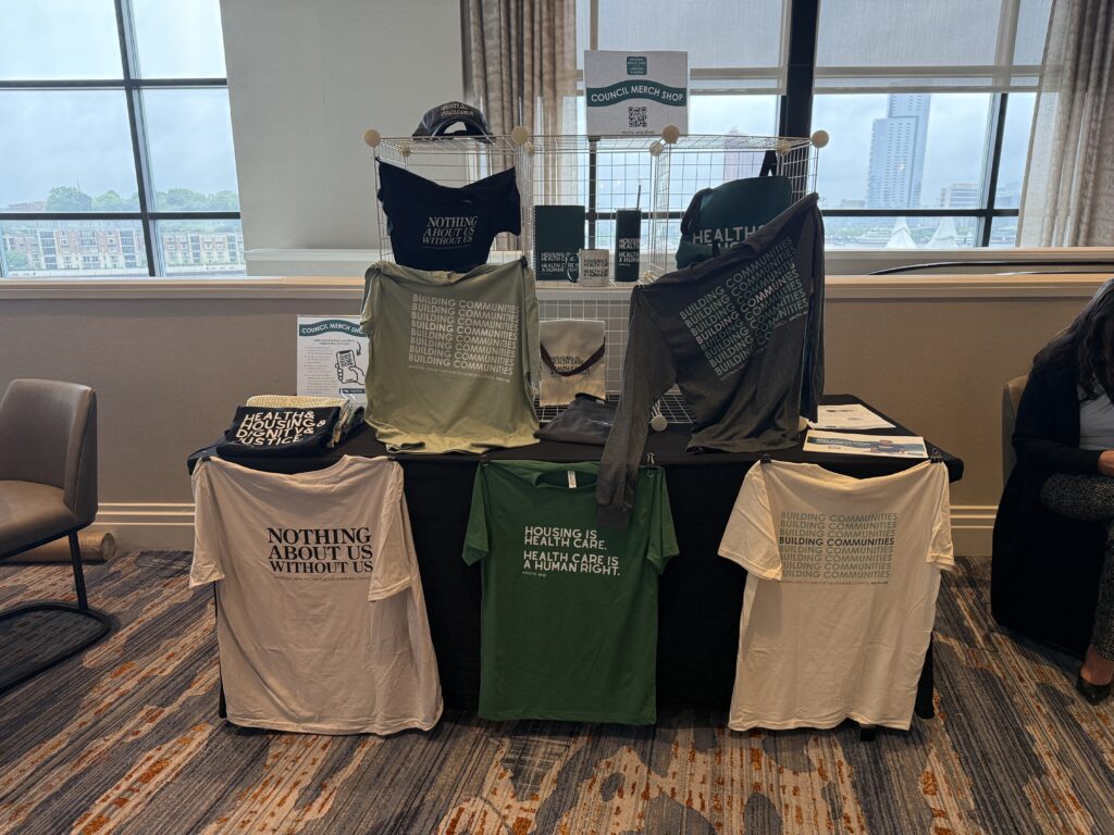 A merch table at a conference displaying shirts and mugs